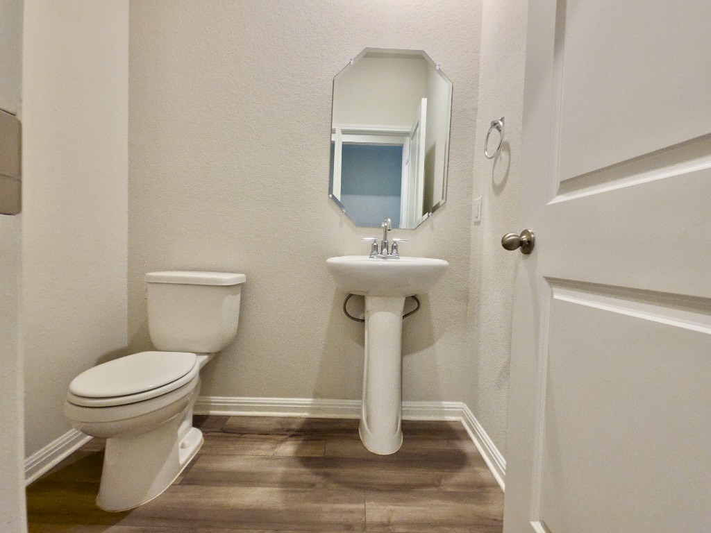 110 Grapefruit Road Hutto, TX 78634 - Photo 26 of 28 Pedestal sink with an octagonal mirror, chrome faucet, and wood-finish flooring