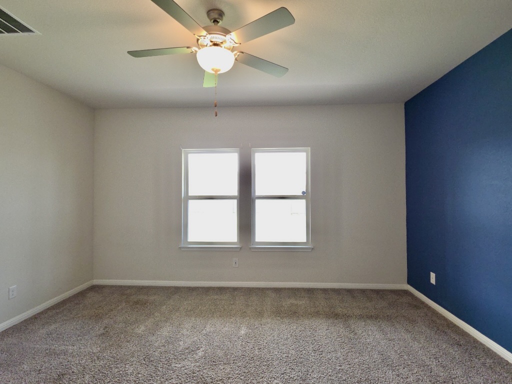 110 Grapefruit Road Hutto, TX 78634 - Photo 9 of 28 Bedroom with a ceiling fan, two windows, and textured carpet flooring