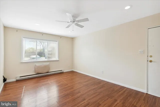 an empty room with wooden floor fan and windows