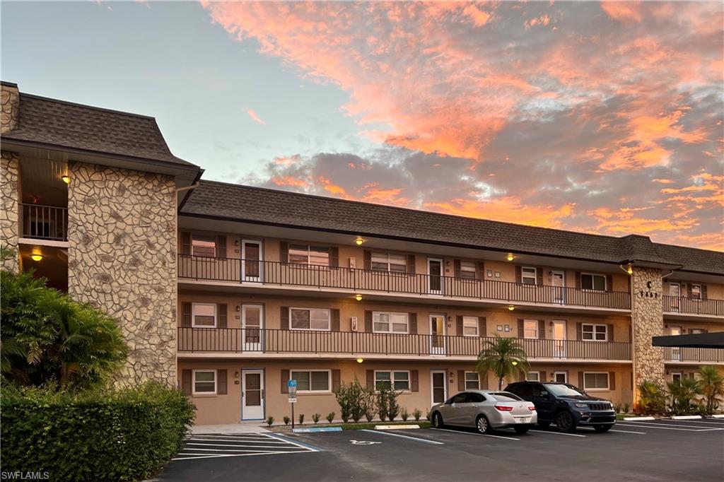 5467 Rattlesnake Hammock Road, Unit 202C Naples, FL 34113 - Photo 17 of 18 a front view of a building with lot of cars and trees