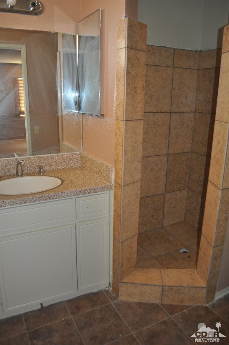 46531 Vargas Road Indio, CA 92201 - Photo 14 of 18 a bathroom with a granite countertop sink a mirror and shower