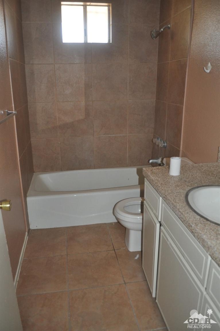 46531 Vargas Road Indio, CA 92201 - Photo 8 of 18 a bathroom with a granite countertop sink a toilet a mirror and shower
