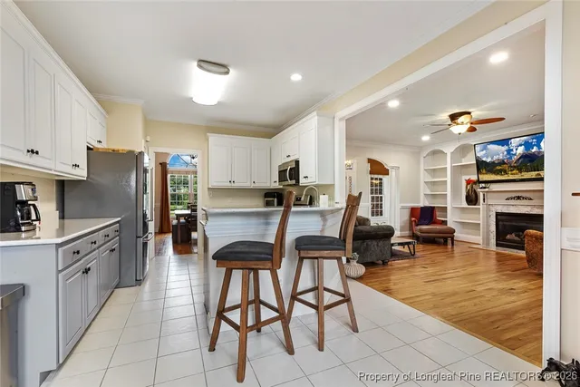 a kitchen with stainless steel appliances granite countertop a stove top oven a sink a dining table and chairs with wooden floor