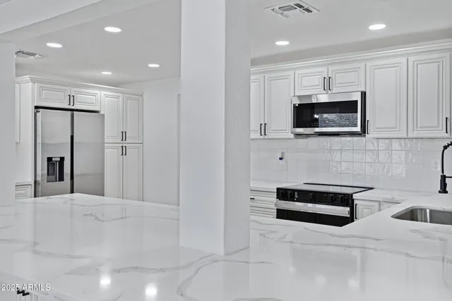 a large kitchen with stainless steel appliances kitchen island granite countertop a sink and cabinets