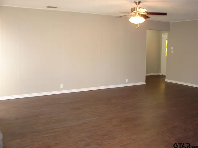 an empty room with wooden floor and fan