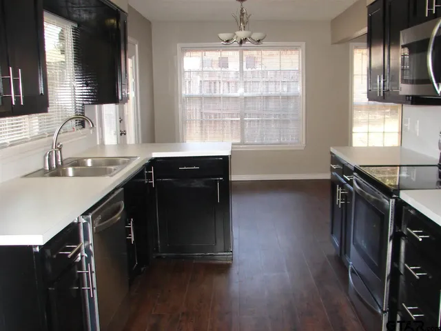 a kitchen with granite countertop a sink cabinets and wooden floor