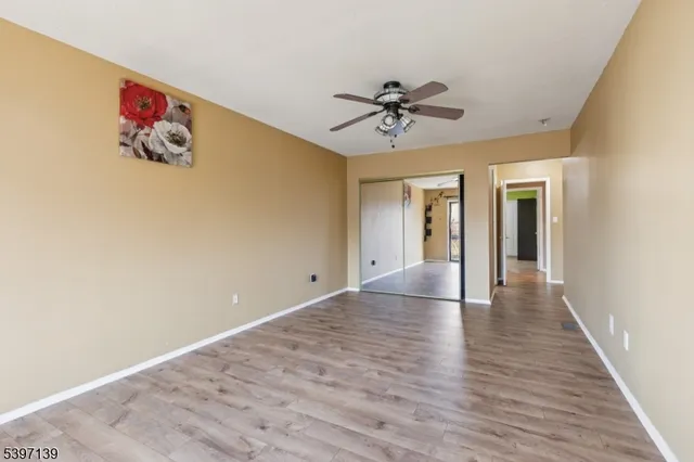 a view of a hallway with wooden floor and a chandelier fan