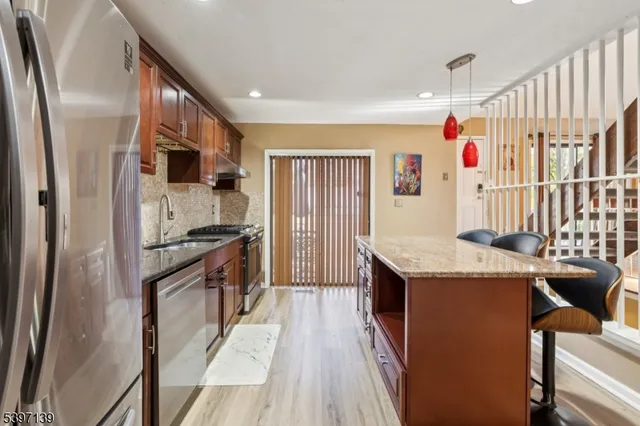 a kitchen with stainless steel appliances granite countertop a refrigerator a stove and a sink