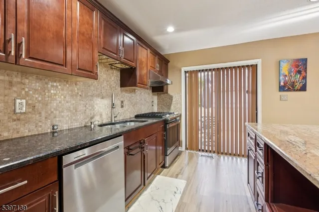 a kitchen with granite countertop wooden cabinets a sink and dishwasher