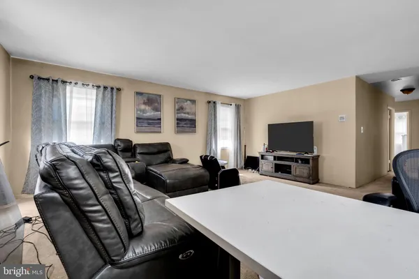 a living room with furniture a flat screen tv and large windows
