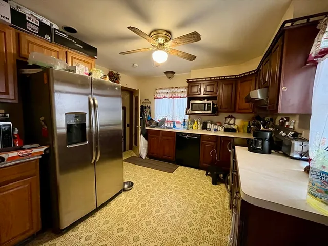 a kitchen with stainless steel appliances kitchen island granite countertop a refrigerator a stove and a sink with wooden floor