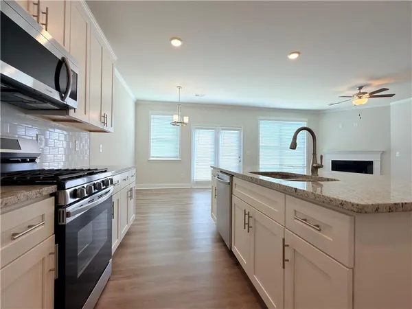 a kitchen with stainless steel appliances granite countertop a stove top oven a refrigerator a sink and dishwasher with white cabinets