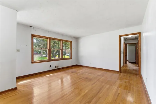 a view of an empty room with a window and wooden floor