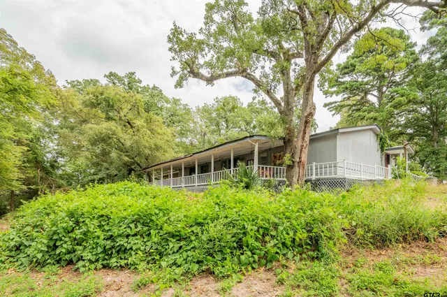 front view of house with a yard and trees all around