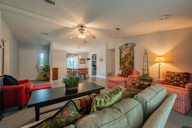 a living room with furniture kitchen view and a chandelier