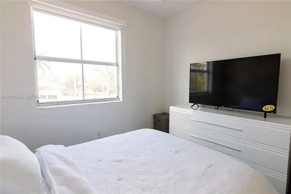 a bedroom with a bed and a window with wooden floor