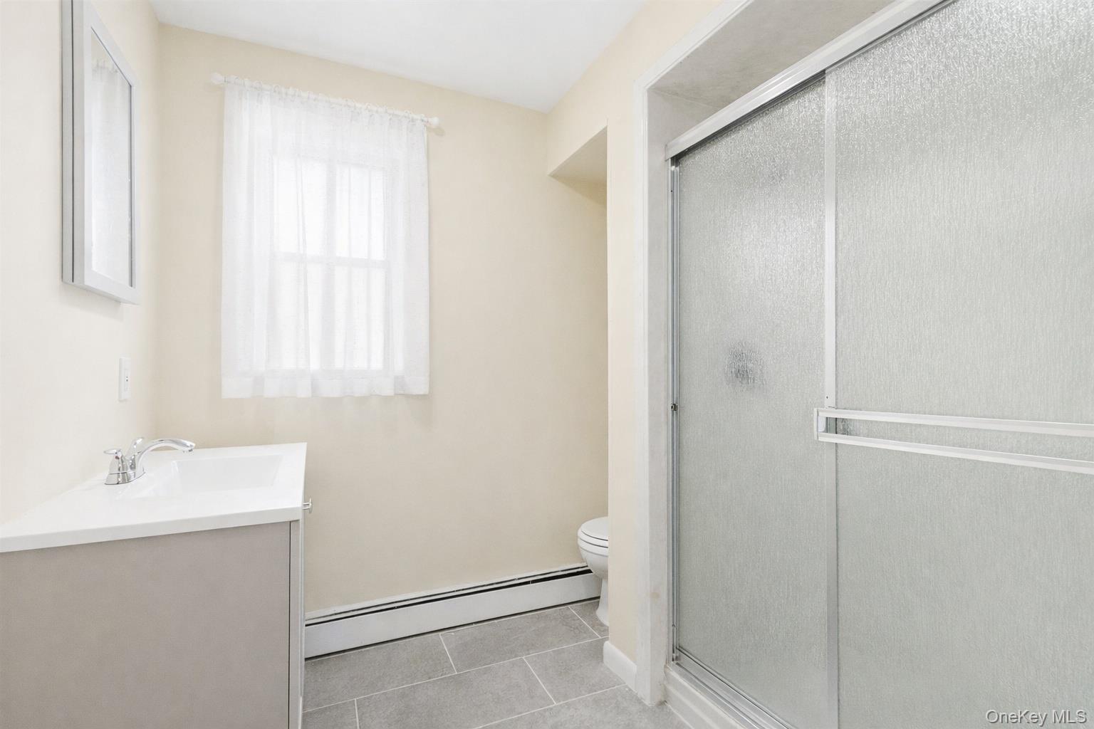 32 North Clover Street Poughkeepsie, NY 12601 - Photo 17 of 20 1st Floor Bathroom featuring a stall shower, a baseboard radiator, vanity, and light tile patterned floors