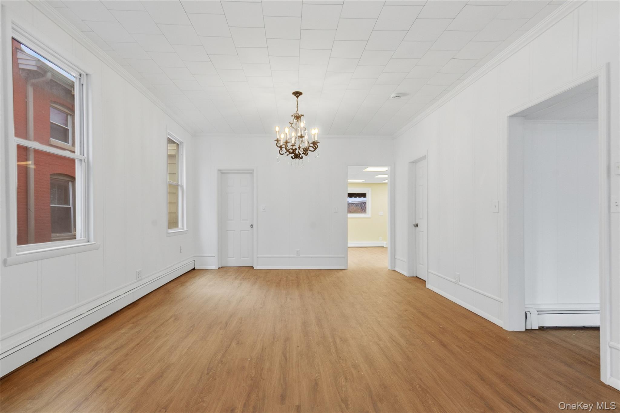 32 North Clover Street Poughkeepsie, NY 12601 - Photo 4 of 20 Unfurnished dining area with a chandelier, a baseboard heating unit, light wood-style floors, and crown molding