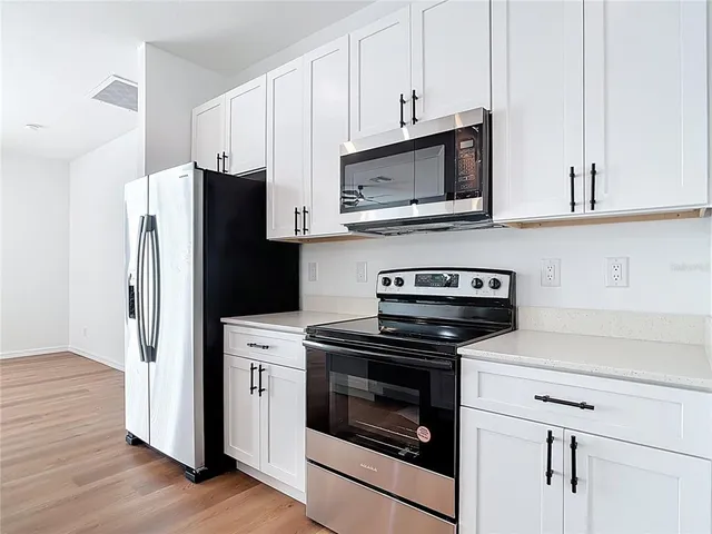 a kitchen with cabinets stainless steel appliances and wooden floor