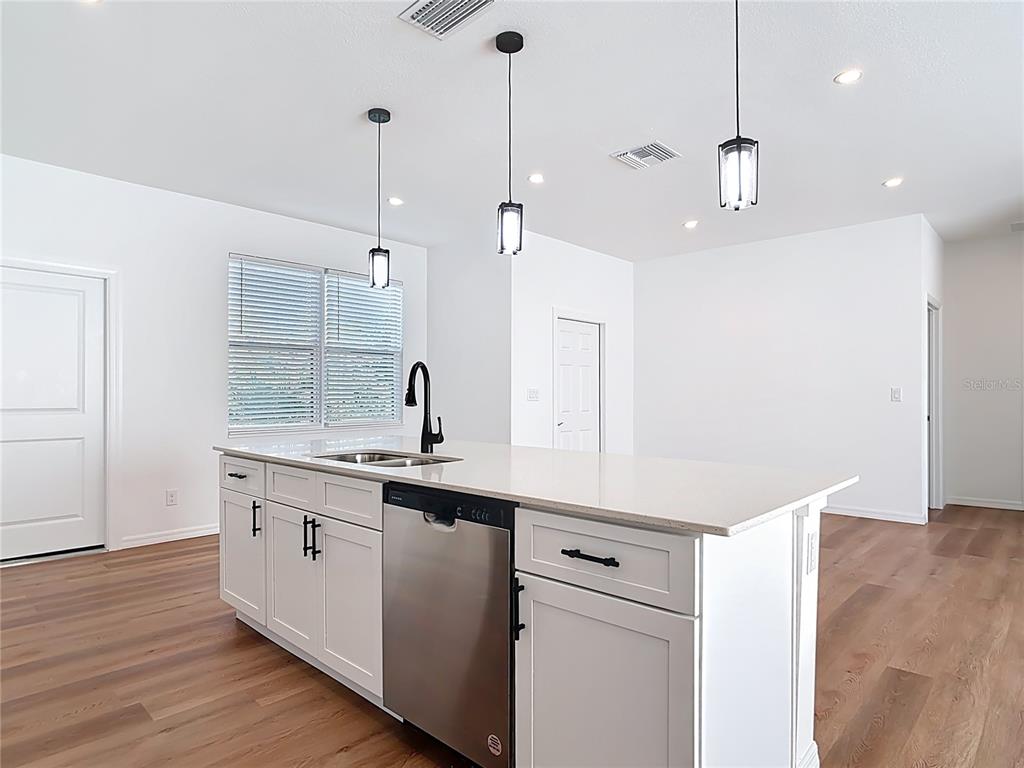 1204 Goshen Road North Port, FL 34288 - Photo 13 of 46 a kitchen with a sink a center island a wooden floor and a window