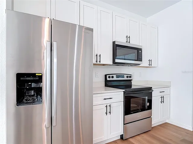 a kitchen with stainless steel appliances white cabinets and a refrigerator