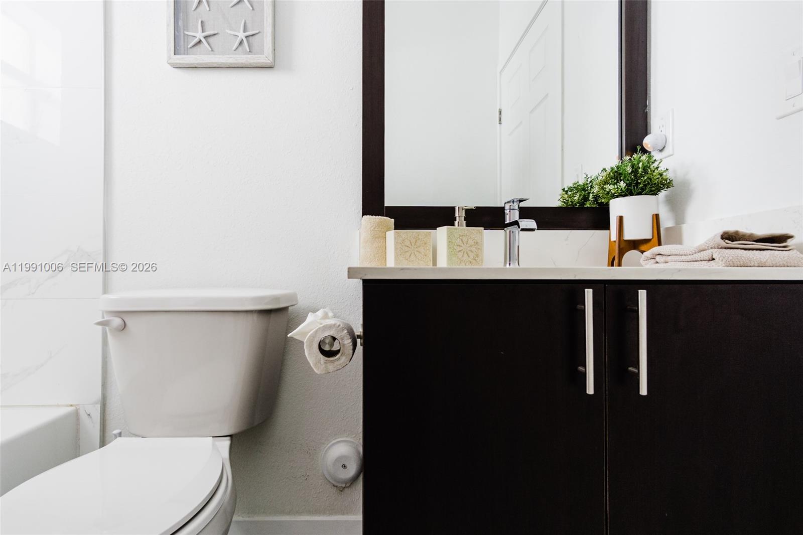 8765 Northwest 22nd Place Miami, FL 33147 - Photo 29 of 37 a bathroom with a sink a toilet and mirror
