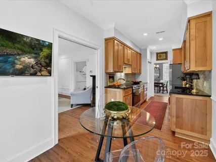 a living room with stainless steel appliances furniture a rug and a kitchen view