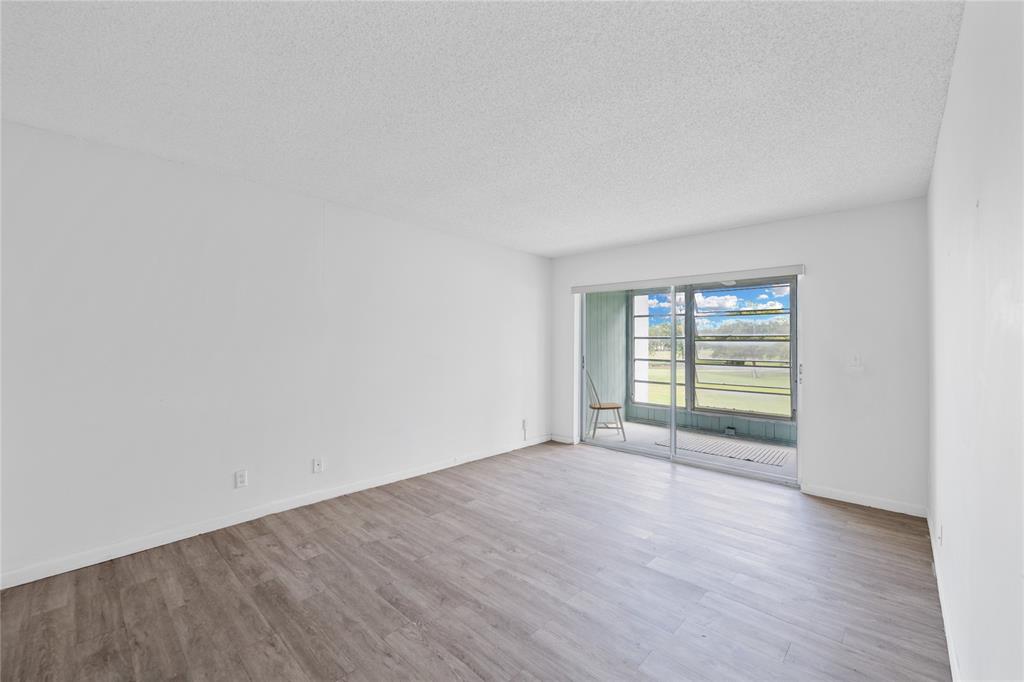 8105 Northwest 61st Street, Unit A206 Tamarac, FL 33321 - Photo 11 of 44 a view of an empty room with wooden floor and a window