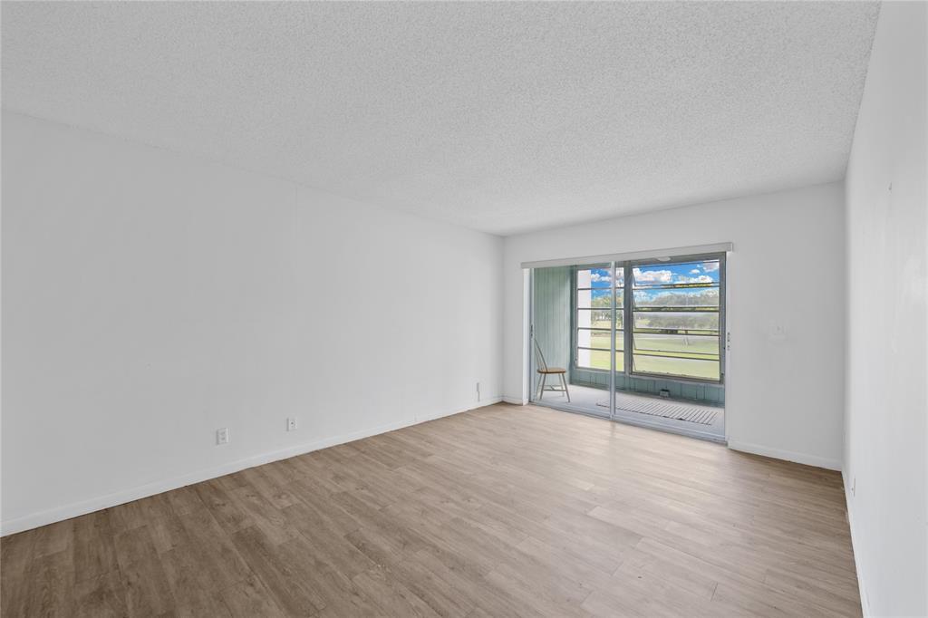 8105 Northwest 61st Street, Unit A206 Tamarac, FL 33321 - Photo 10 of 44 a view of an empty room with wooden floor and a window