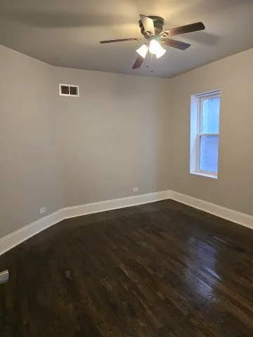 a view of room with hardwood floor and a ceiling fan