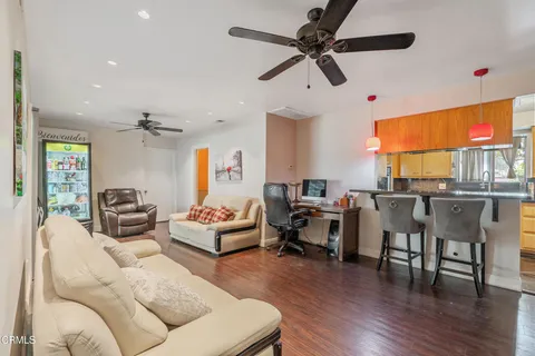 a living room with furniture kitchen view and a wooden floor