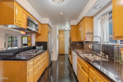 a kitchen with stainless steel appliances granite countertop a sink a stove and a refrigerator