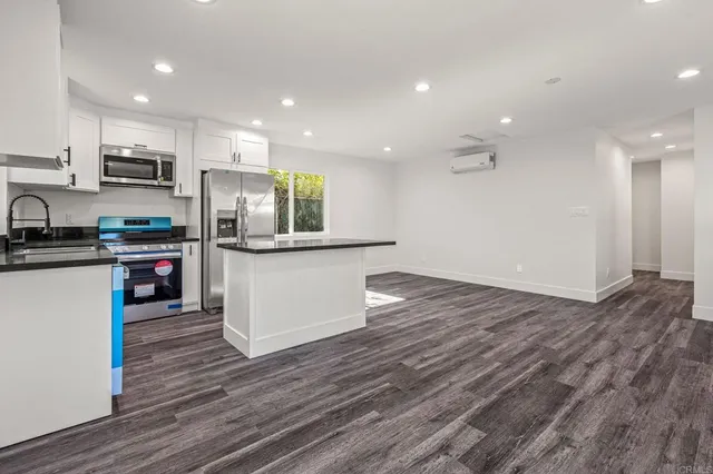 an empty room with wooden floor and a kitchen