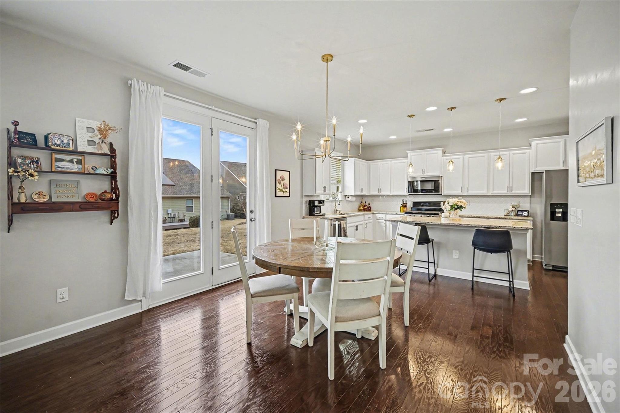 18314 McKee Road Charlotte, NC 28278 - Photo 14 of 37 a kitchen with stainless steel appliances kitchen island granite countertop a refrigerator a stove a dining table and chairs with wooden floor