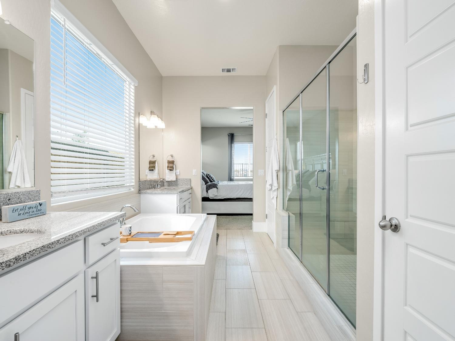 4289 Vineyard Drive Madera, CA 93636 - Photo 16 of 37 a en suite bathroom with a granite countertop sink mirror and a bathtub