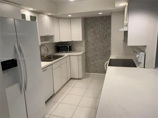 a kitchen with a sink a refrigerator and cabinets