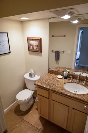 a bathroom with a granite countertop toilet a sink and a mirror