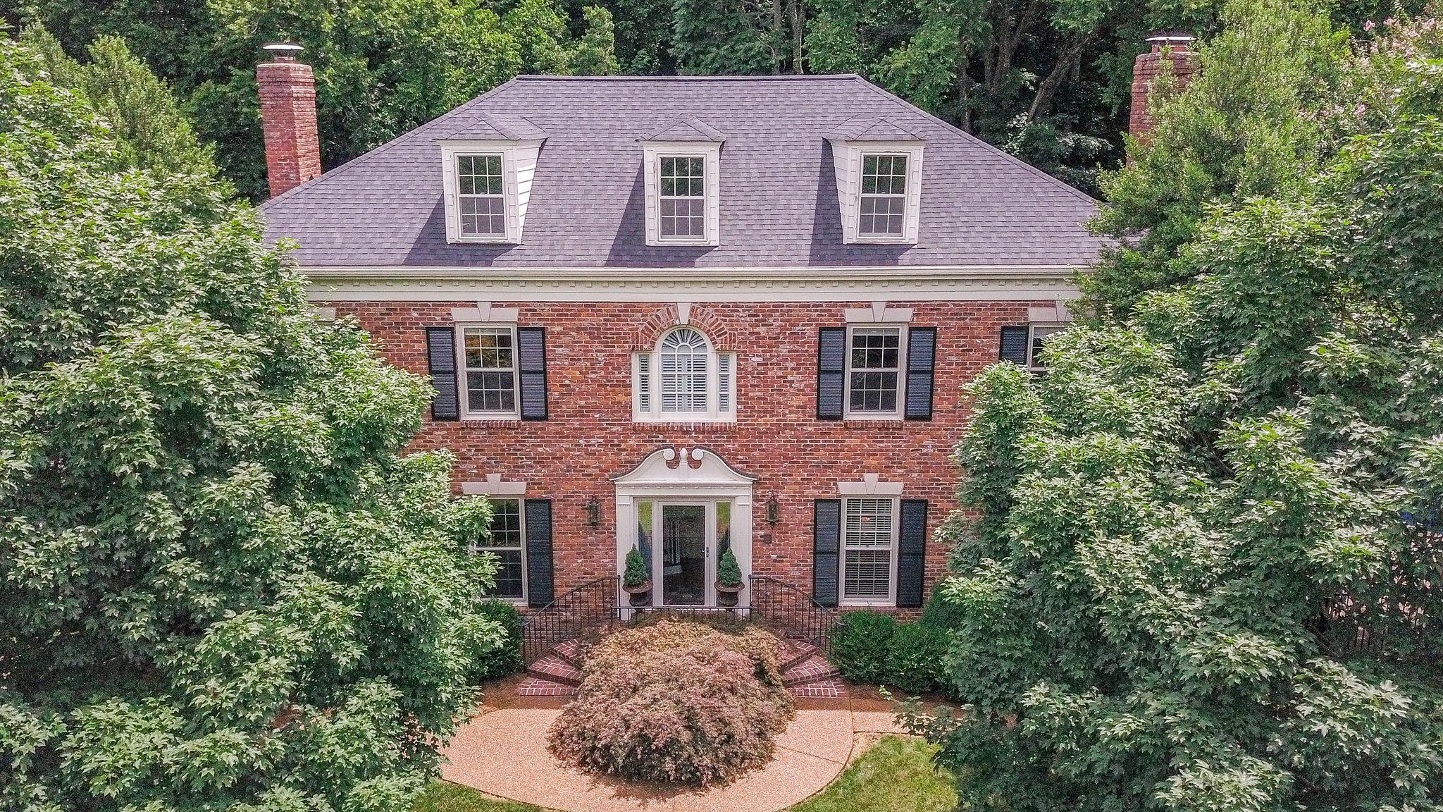 a aerial view of a house with yard and trees