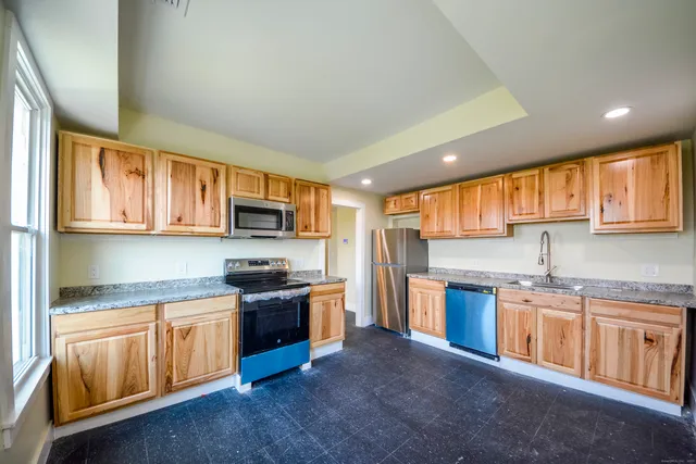 a kitchen with stainless steel appliances granite countertop a stove top oven a sink dishwasher a refrigerator and cabinets with wooden floor