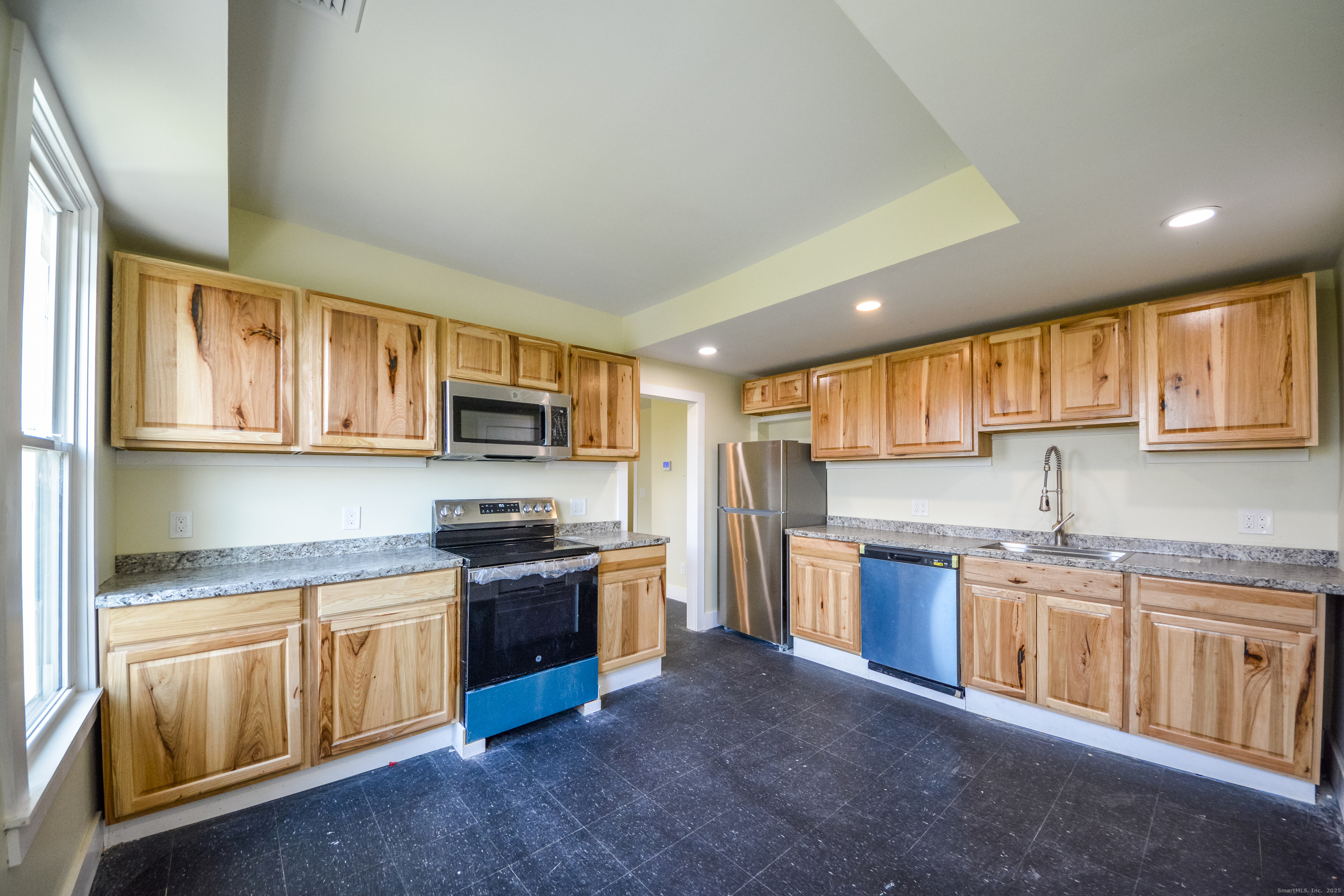 a kitchen with stainless steel appliances granite countertop a stove top oven a sink dishwasher a refrigerator and cabinets with wooden floor