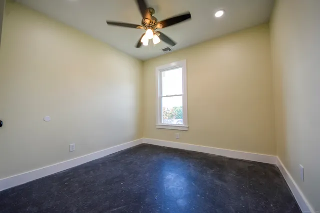 an empty room with a window and a fan