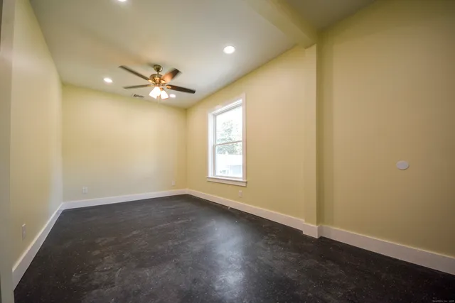 an empty room with windows and fan