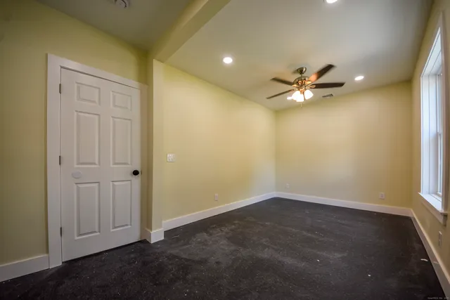 an empty room with a chandelier fan and windows