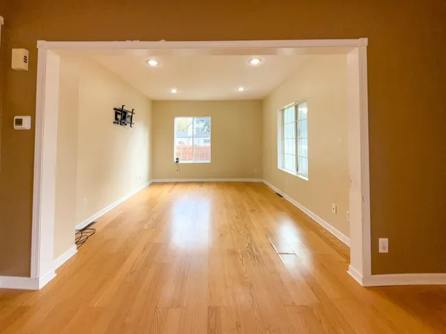 a view of a big room with wooden floor and windows