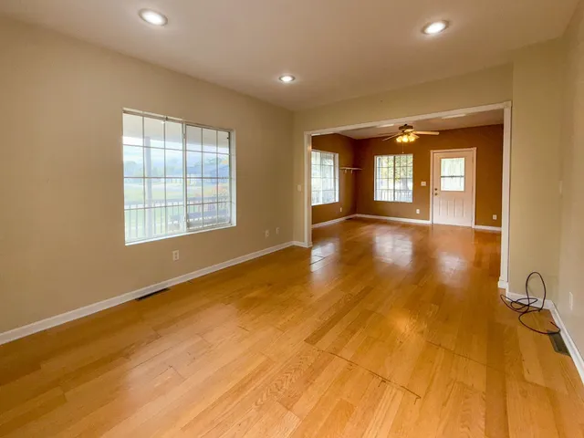 a view of an empty room with a window and wooden floor