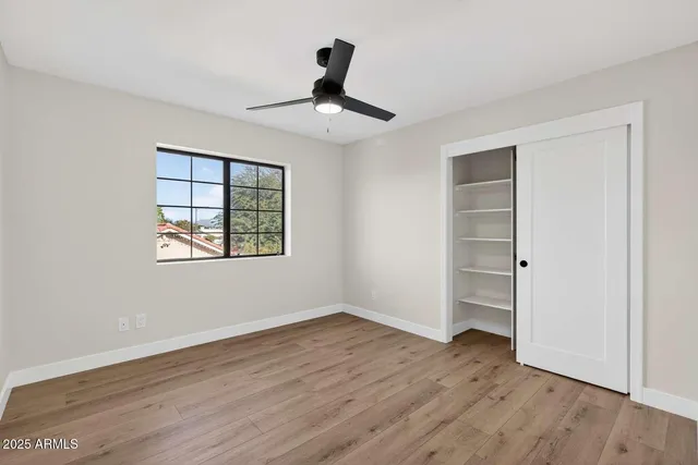 an empty room with wooden floor cabinet and windows