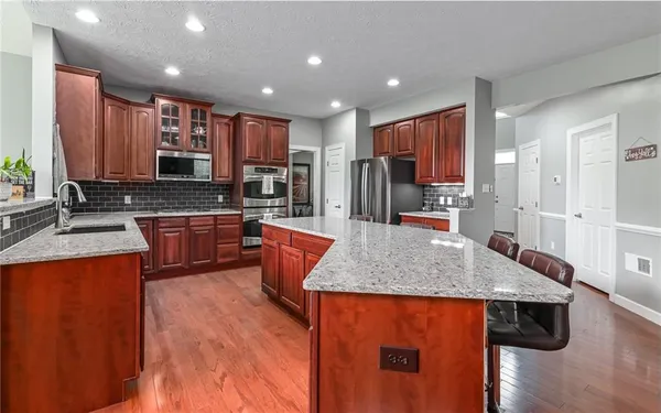 a kitchen with granite countertop a sink stove and refrigerator