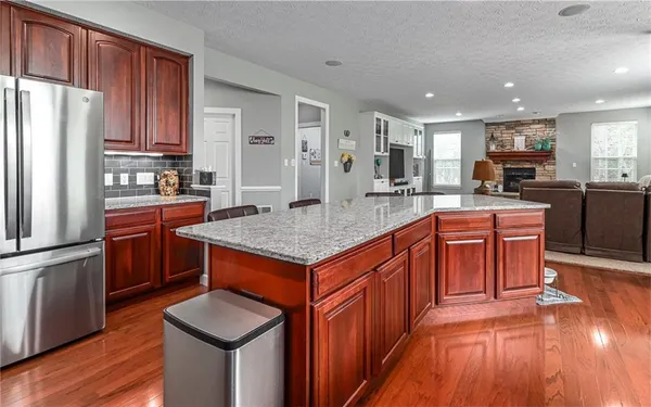 a kitchen with stainless steel appliances granite countertop a stove top oven a sink dishwasher a dining table and chairs with wooden floor