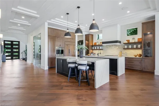 a kitchen with stainless steel appliances kitchen island granite countertop a stove a sink a refrigerator and a dining table with wooden floor