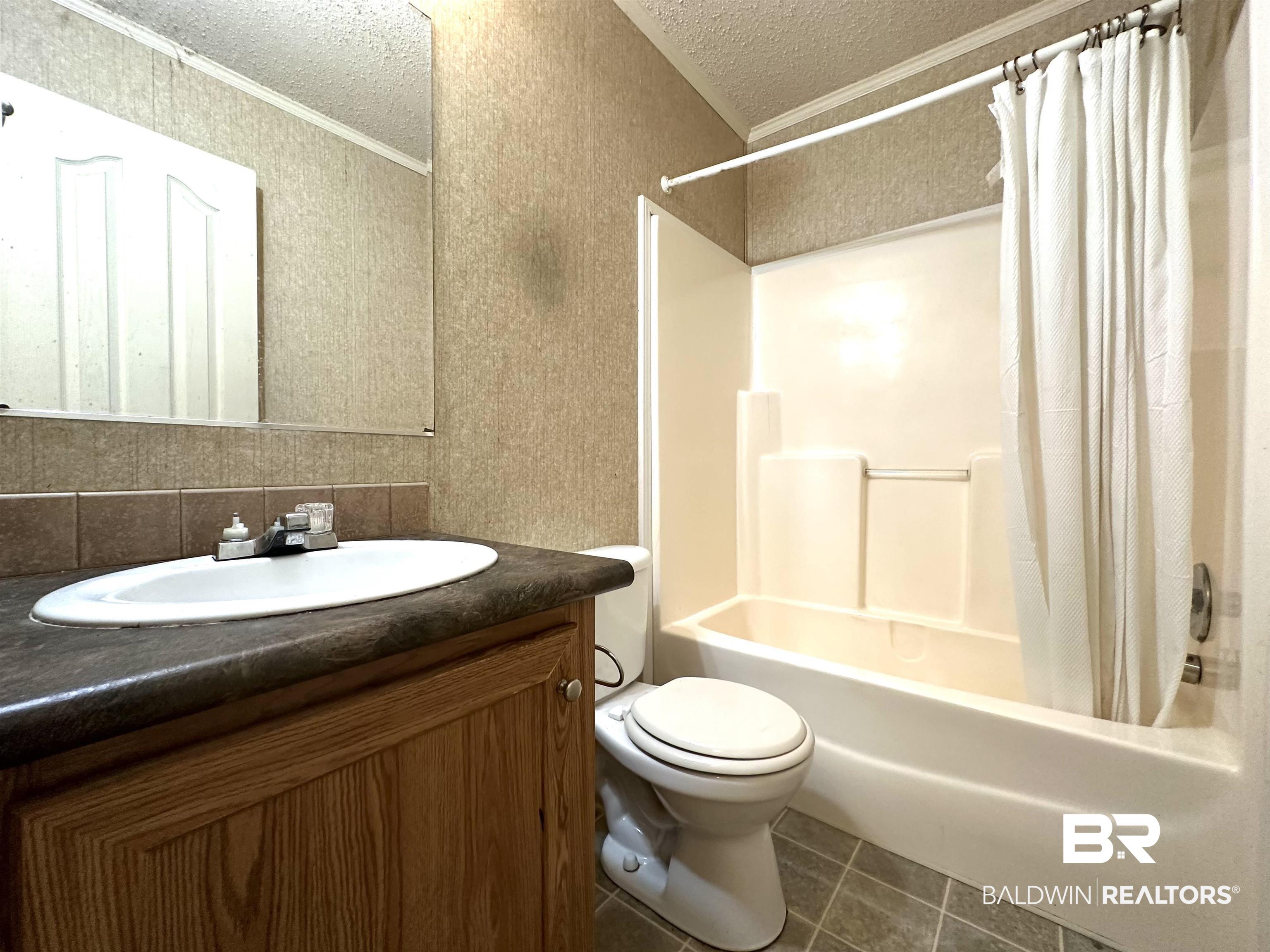 23268 T D Barnett Road Robertsdale, AL 36567 - Photo 15 of 16 Full bathroom with toilet, tile patterned floors, vanity, a textured ceiling, and backsplash